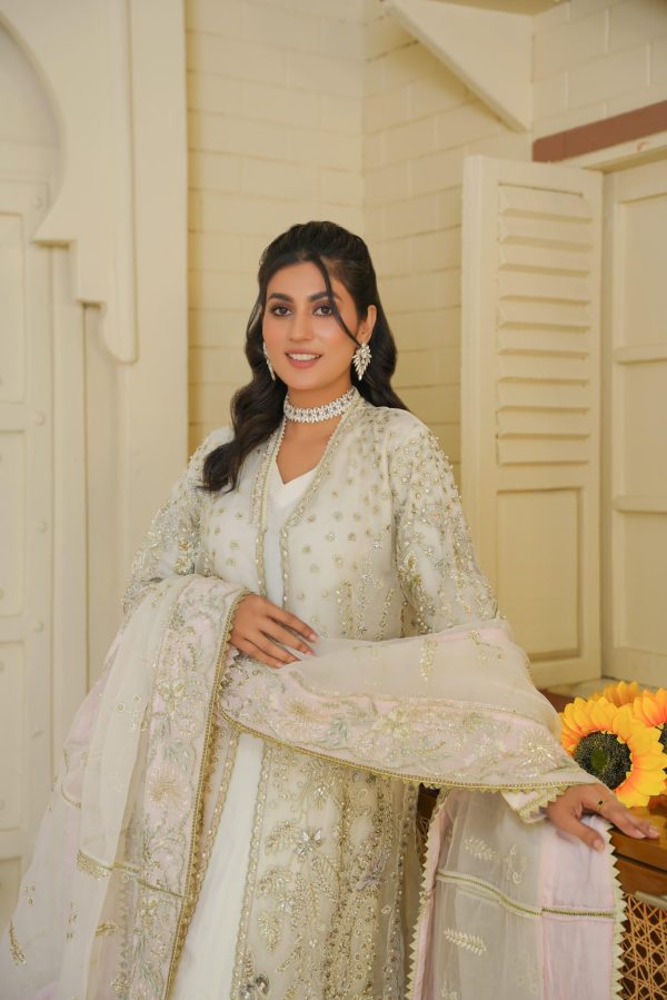 A girl in white embroidered suit, standing next to a sunflower.