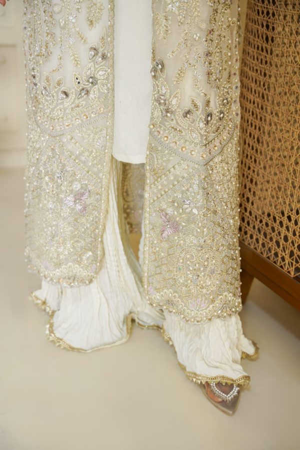 The bottom of white embroidered suit with golden pearls on it.