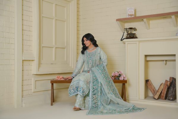 A girl sitting on the bench, wearing ferozi embroidered suit.